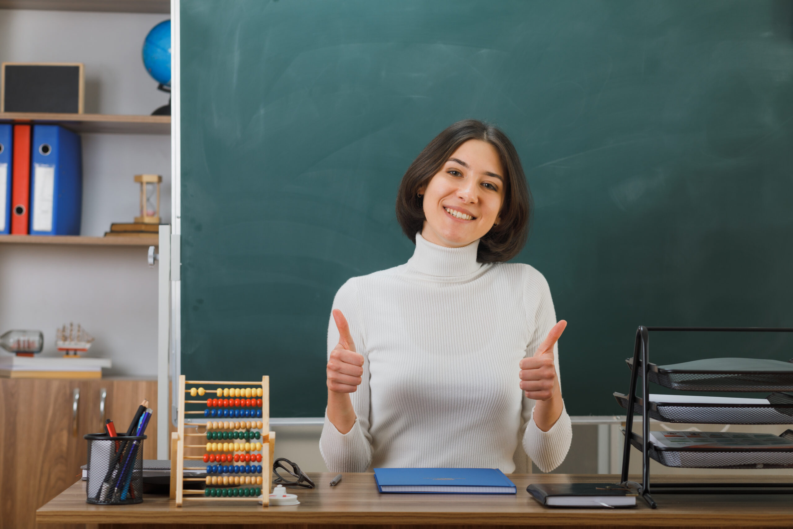 Smiling teacher sitting at a school desk.